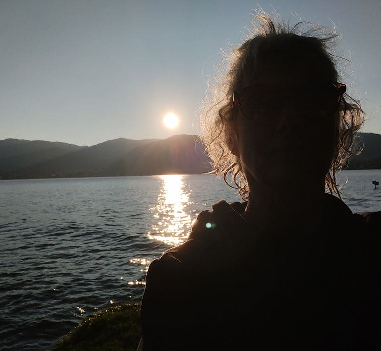 Silhouette von Ute Marth vor einem Sonnenuntergang am Wasser
